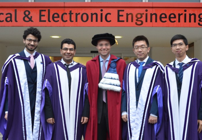 Photo of Professor Clerckx in centre, wearing academic robes, smiling with four graduating students