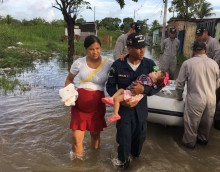 Pregnant woman, with a man and child, wade through flood waters in Brazil.