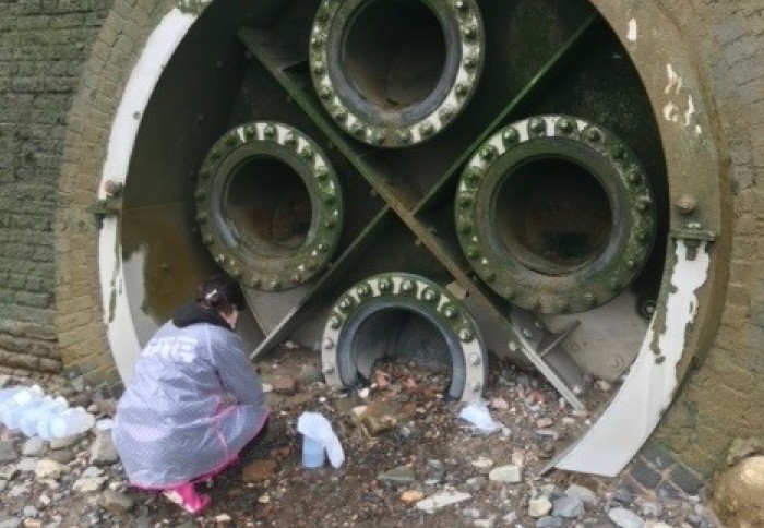 Woman crouched in front of a large pipe