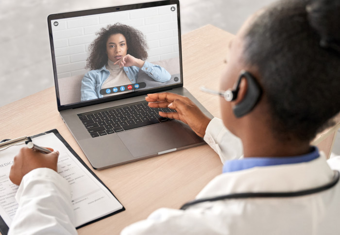 Doctor speaks to patient on screen on a laptop.
