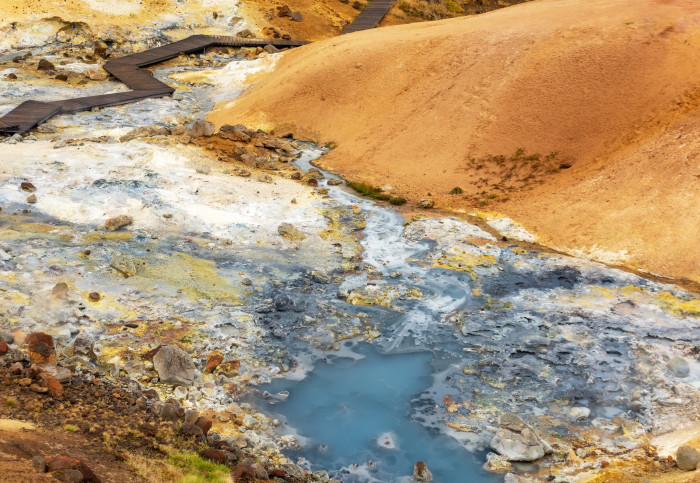 A blue-grey stream surrounded by colourful orange ground