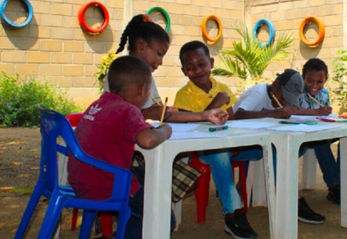 Children drawing on a plastic table outside