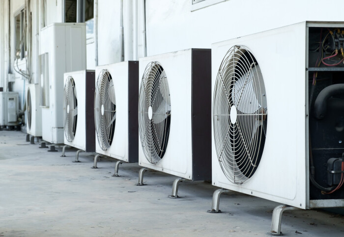 A row of air conditioning compressors outside a building