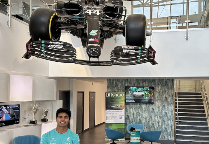 Abhi Rajendran standing underneath an F1 racing car at Mercedes AMG