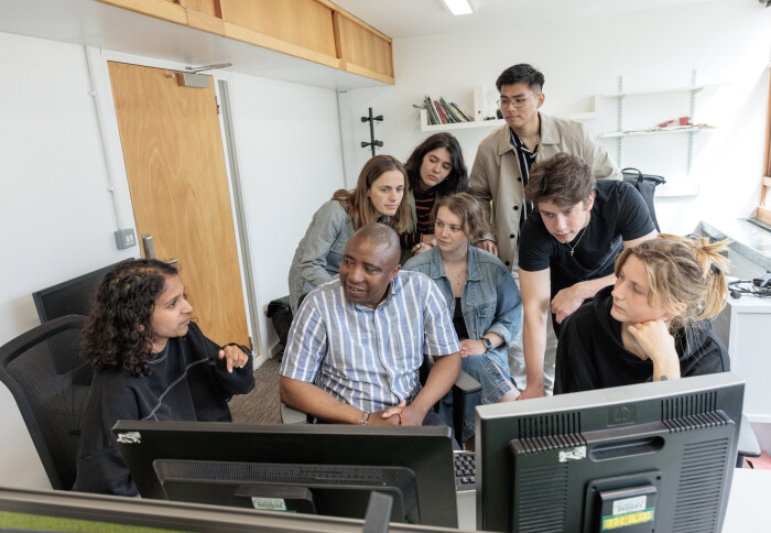 Onesmus sat in front of computer monitors with his students. They're engaged in a lively discussion.