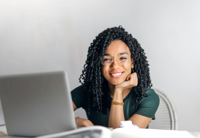 Happy student sitting at table with laptop