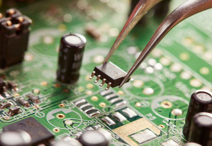 Close up of a person holding a chip above a circuit board