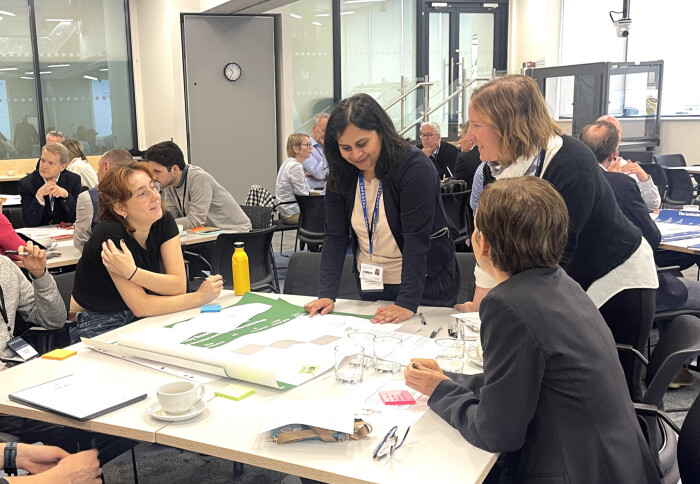 Participants at a workshop standing around and discussing their ideas