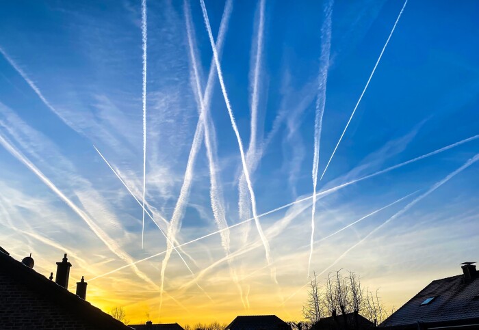 Contrails in an evening sky above houses