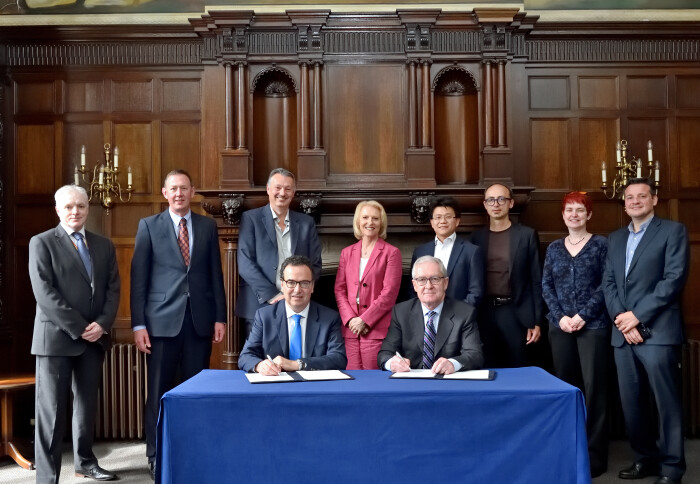 Leaders from IBM and Imperial pose behind a desk