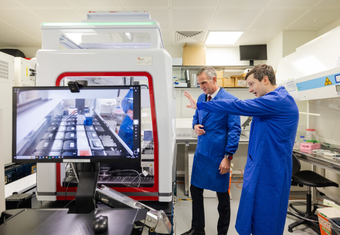 Secretary of State for Science, Innovation and Technology Dr Peter Kyle MP and Cai Linton, Co-Founder and CEO of Multus, together in a laboratory, wearing lab coats and looking at scientific equipment