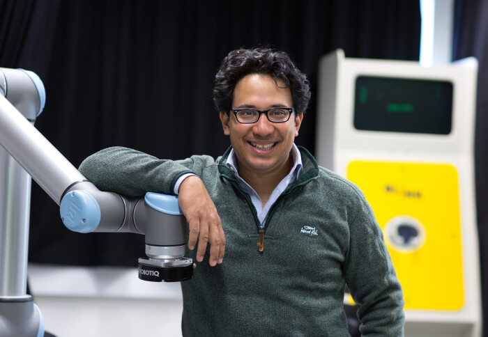 Professor Aldo Faisal stands next to a piece of medical equipment