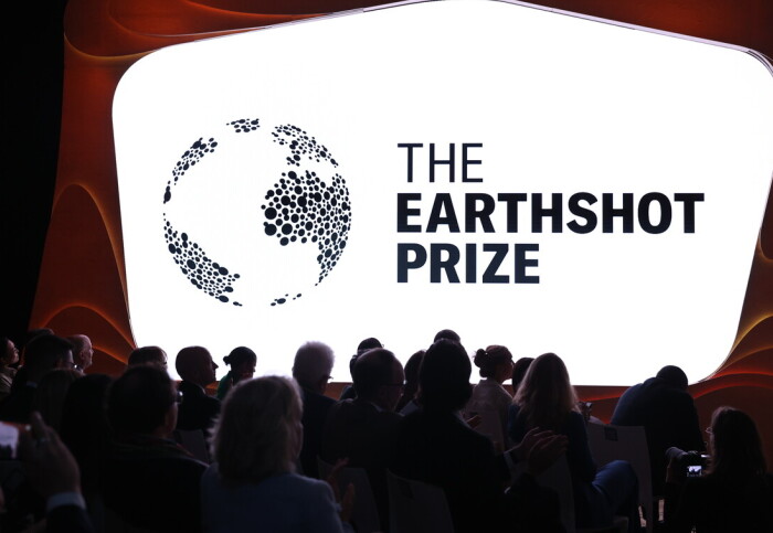 A group of people stood in front of a screen displaying the Earthshot Prize logo