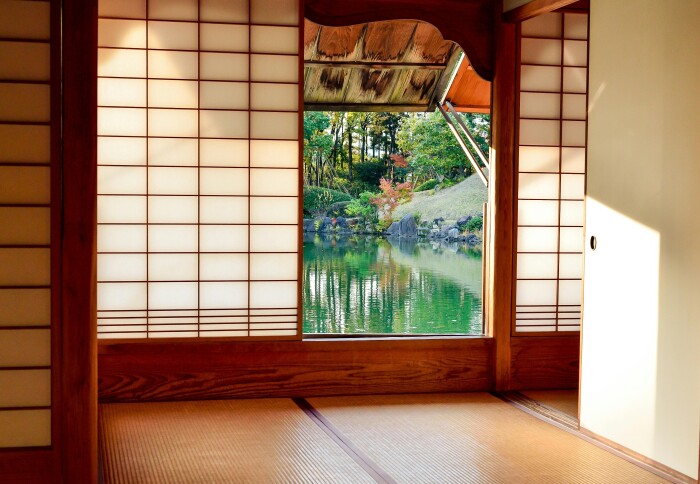 view from inside traditional Japanese building looking through an open door to a body of water in the sunshine