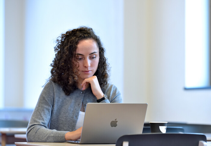 female student with curly hair sat with a laptop