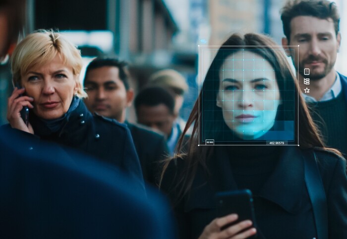 A crowd of people with one woman's face being tracked using technology