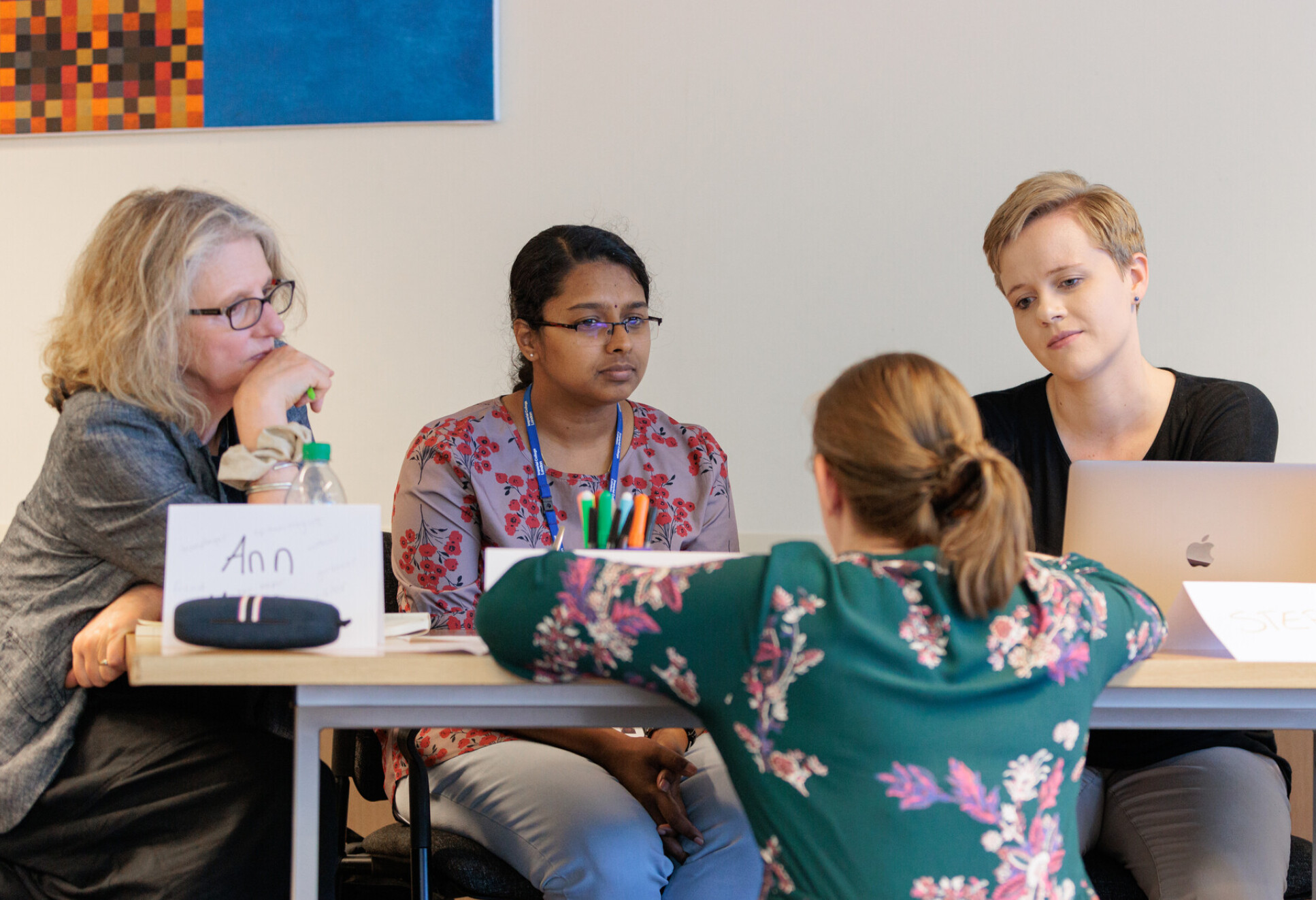 Four women at a desk talking