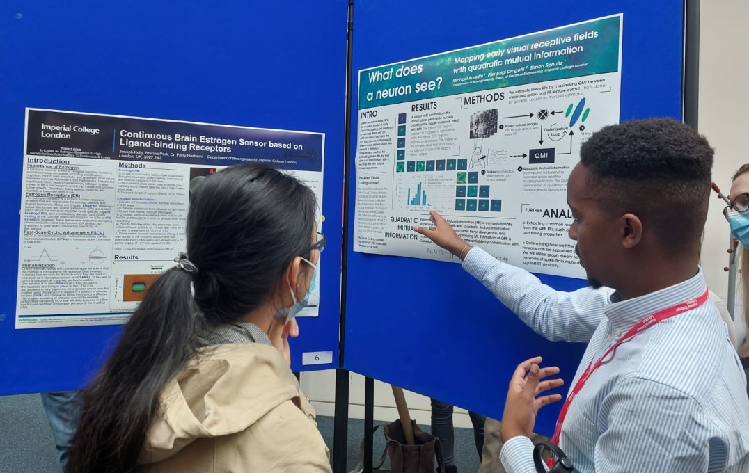 a student explaining his poster to another attendee