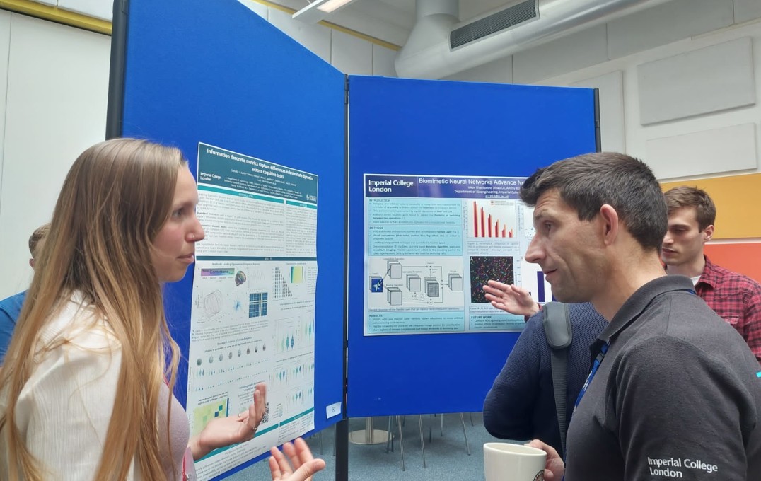 a student describing her poster to another attendee