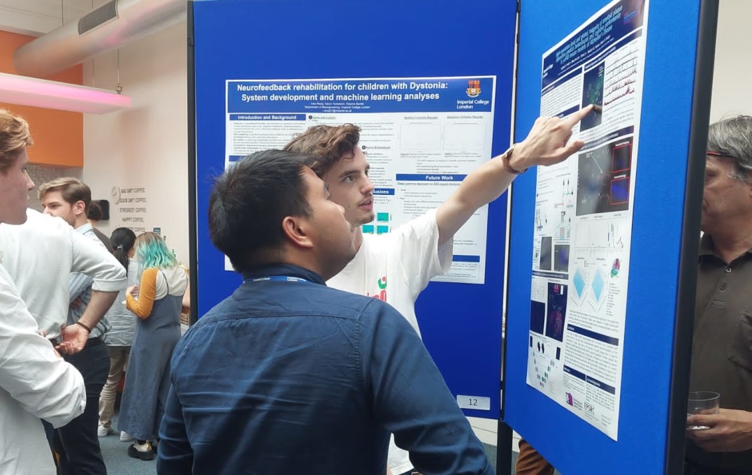 a student explaining his poster to another attendee