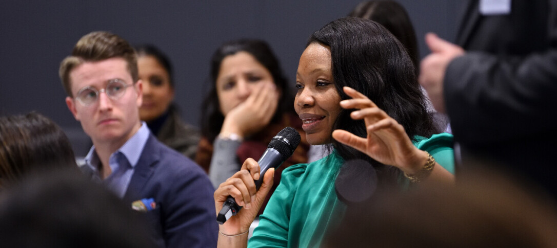 A woman speaking into a microphone at an alumni pnel event