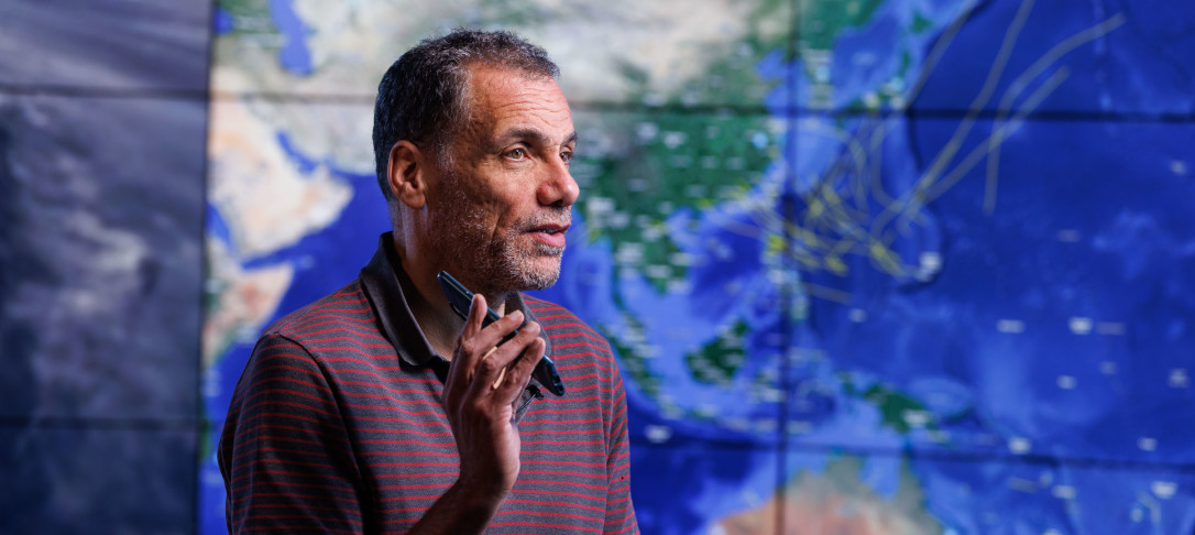 Professor Toumi sitting in front of a digital map, holding a smartphone