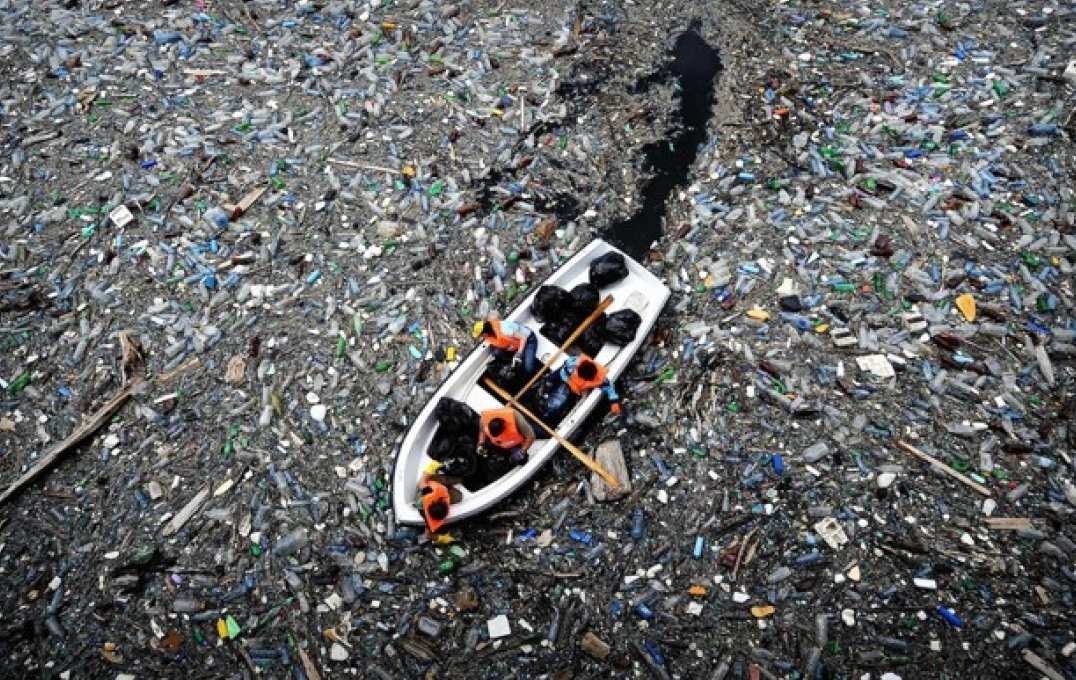 Boat pushes through plastic waste in water