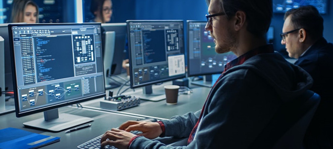 An image of students sitting at computer screens 