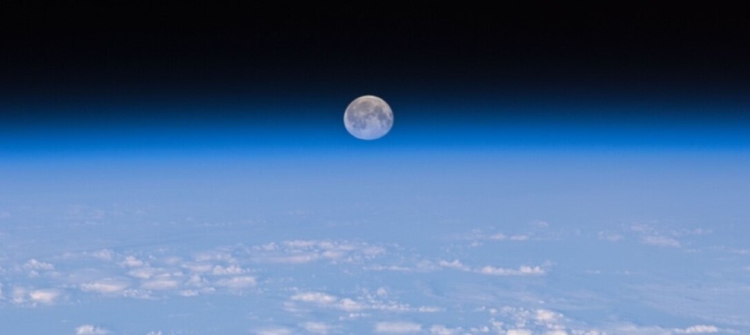 Image showing the Earth's atmosphere and the moon in the background.