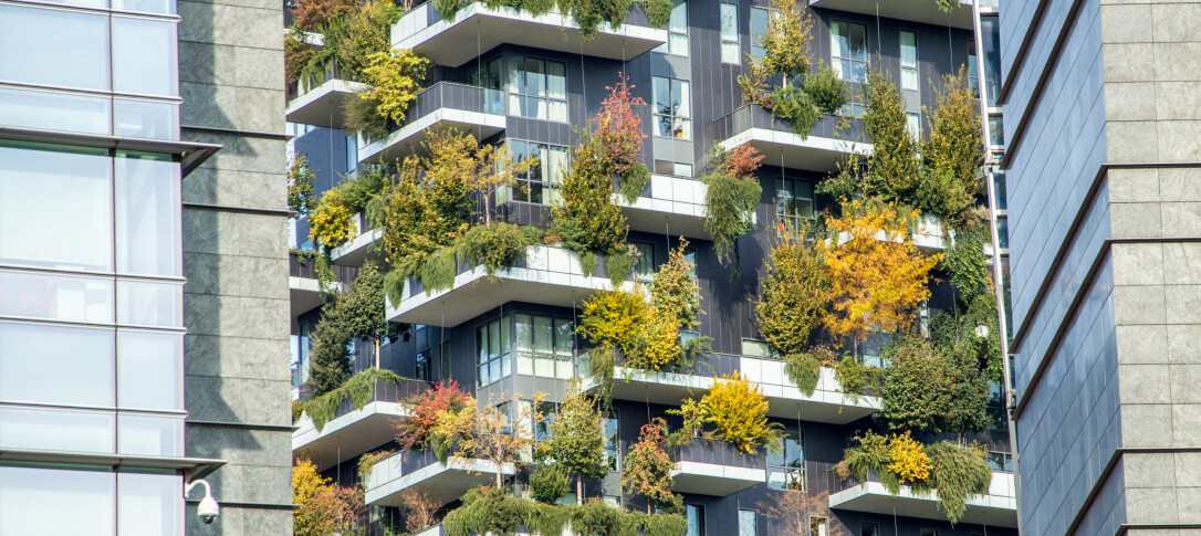 Modern apartment blocks with foliage along the walls and balconies, framed by modern office blocks. Photo is cropped to emphasise the modernity and the contrast between the different buildings. 