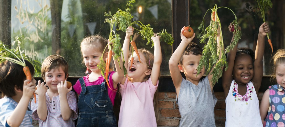 Children smiling and holding vegetables