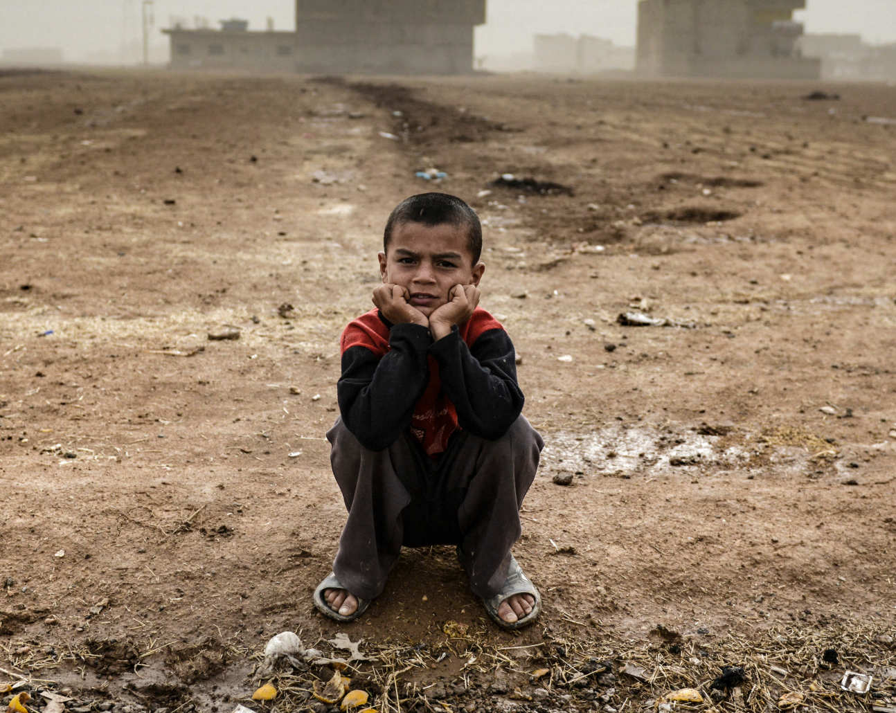 A young boy sitting in a mine field