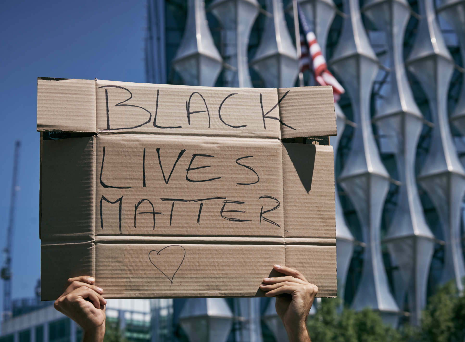 person holds up cardboard which says 'Black Lives Matter'