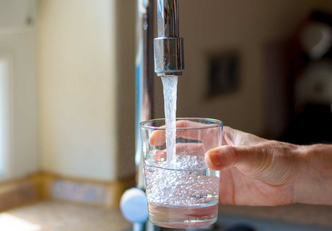 Photo of someone filling a glass with water from a tap