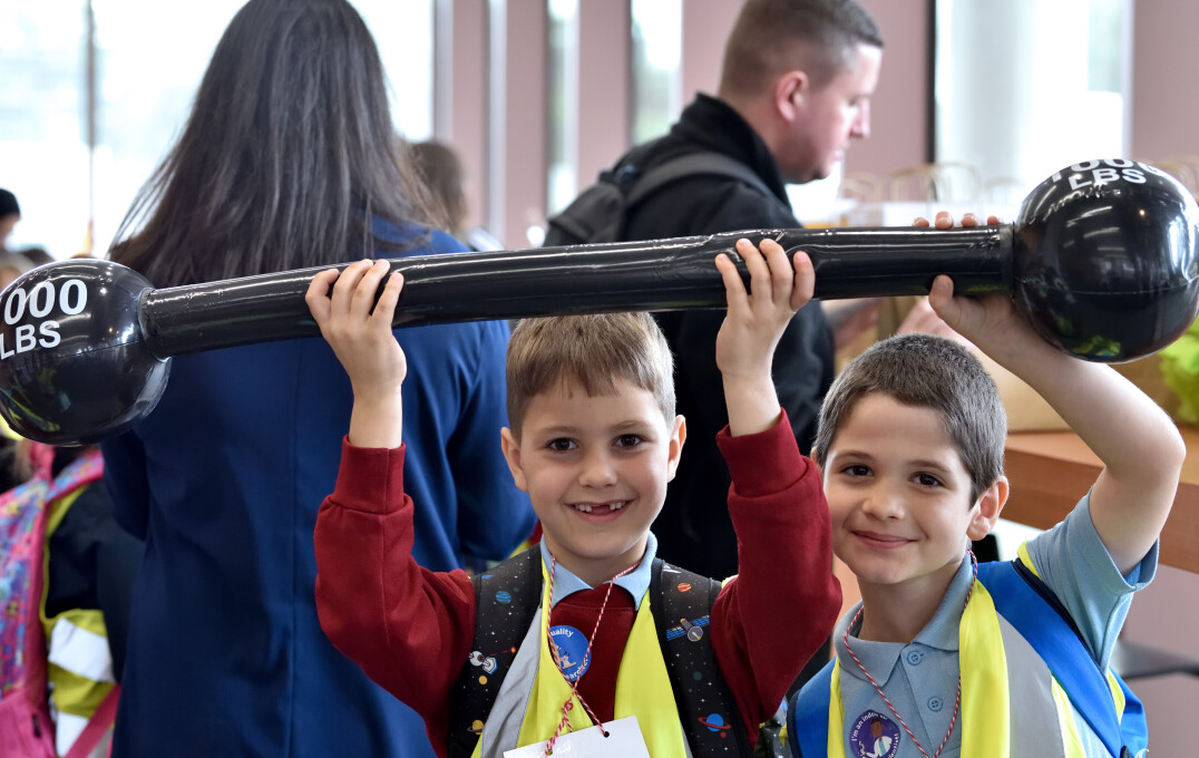 Students hold up a balloon in the shape of a weight