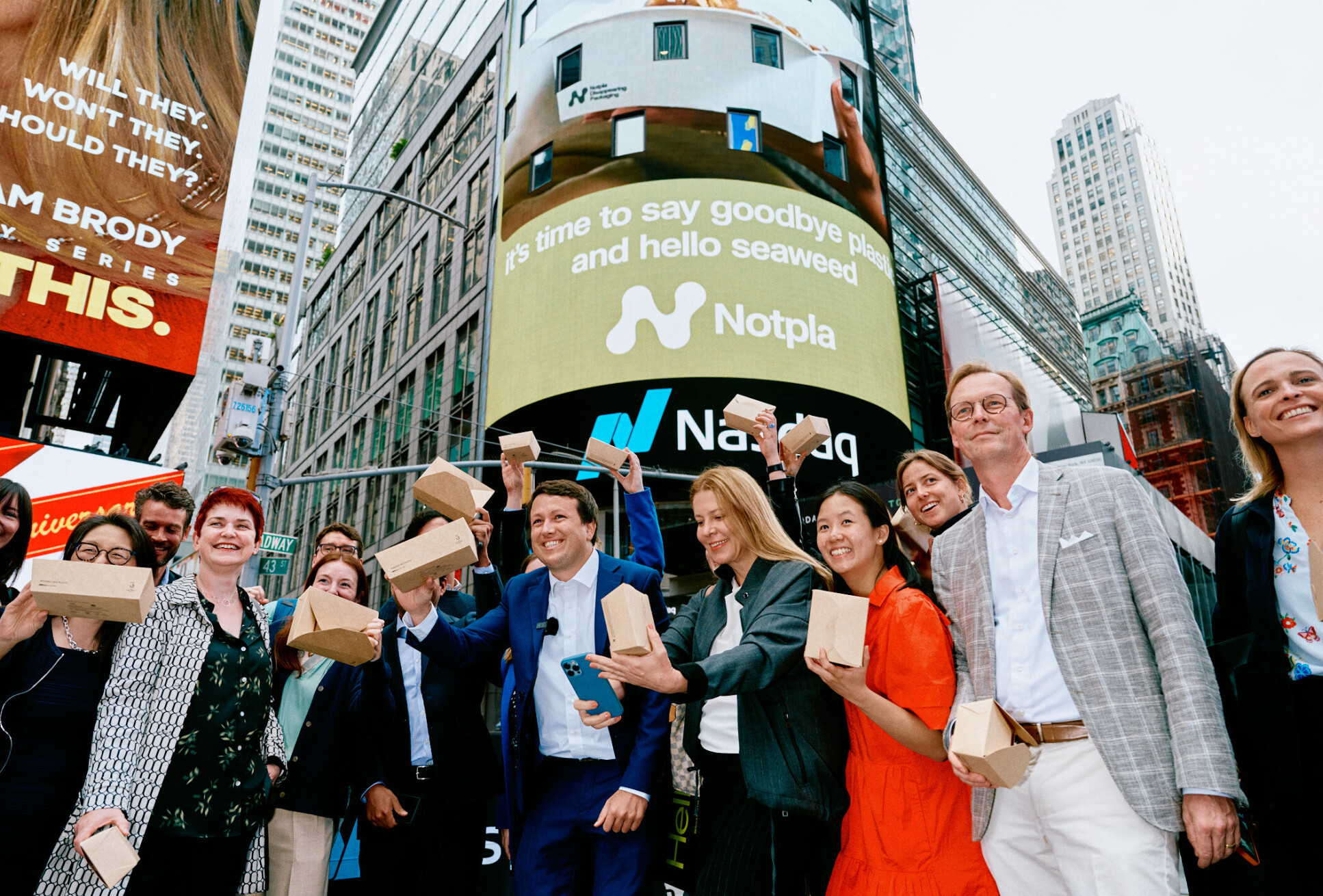 Notpla's logo display's behind a crowd on Times Square