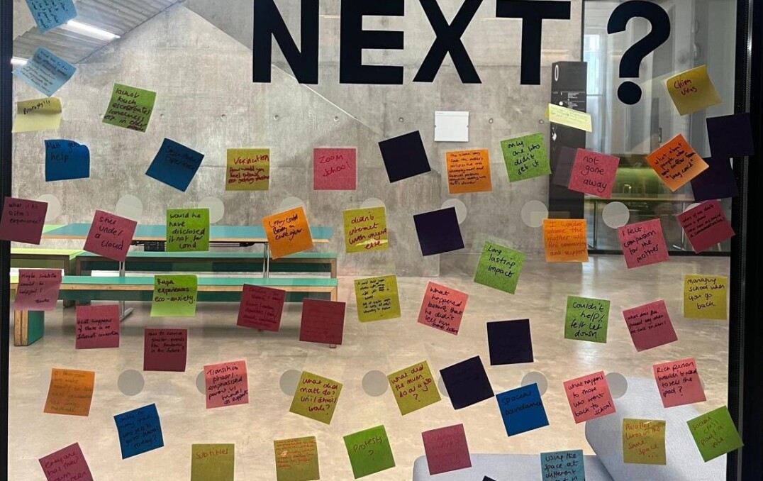 "What happens next?" in large text on a wall, with many coloured post it notes on below.