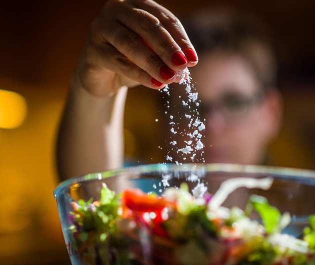 Woman putting salt in a salad