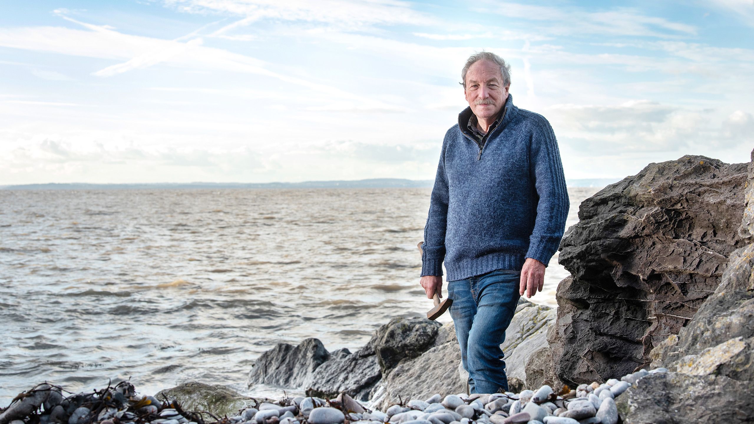 Professor Sir Stephen Sparks stands on a rocky beach looking out over the sea
