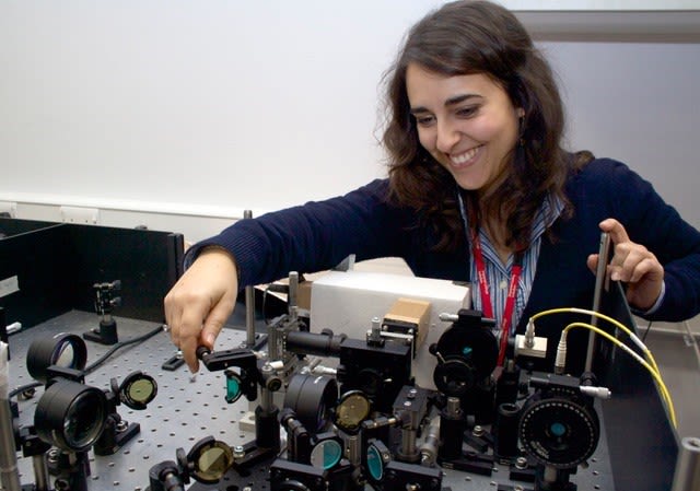 Giuliana working with physics equipment - she is wearing a lanyard around her neck as she touches the pieces on display