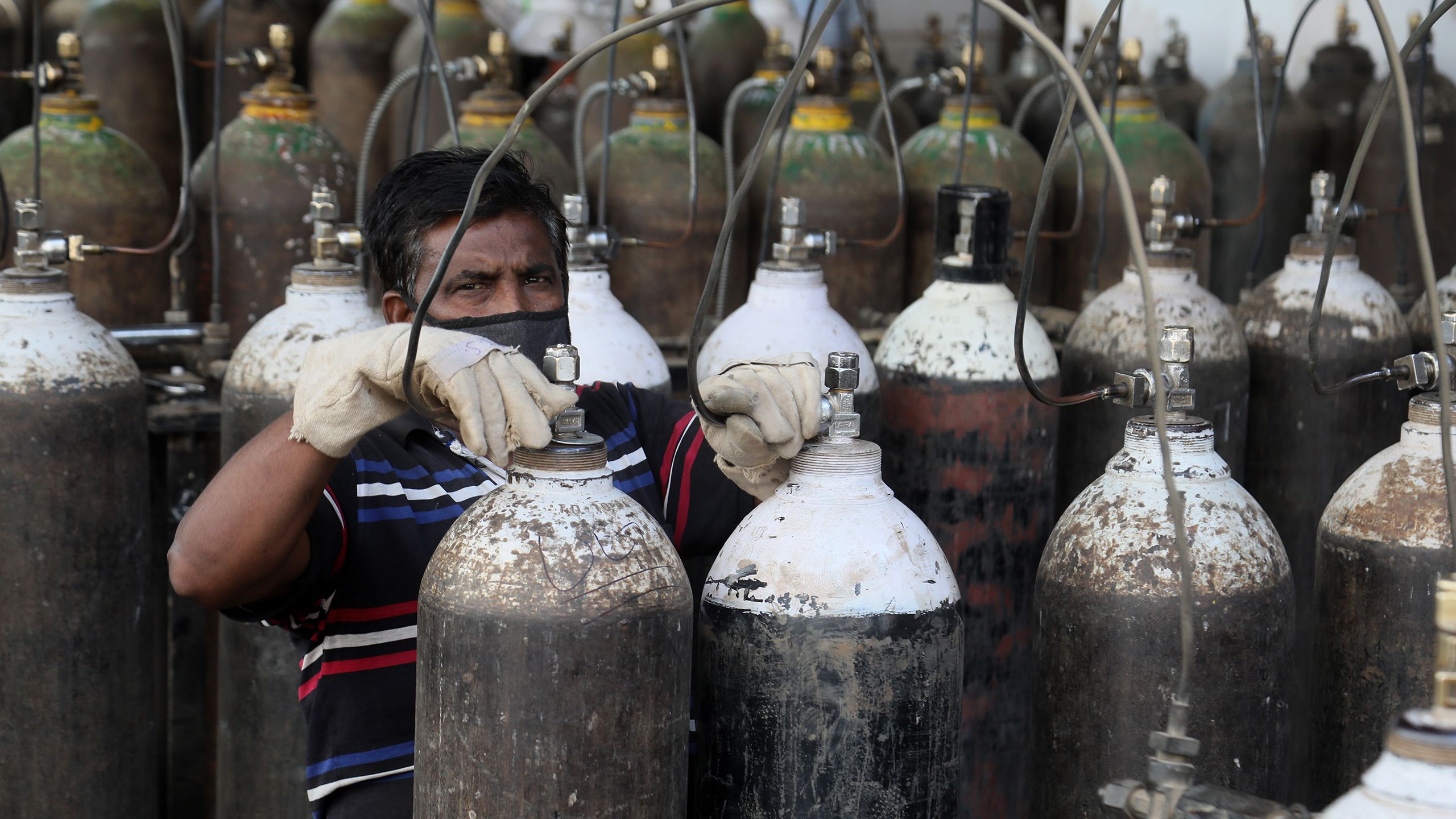 A man refills oxygen canisters in India