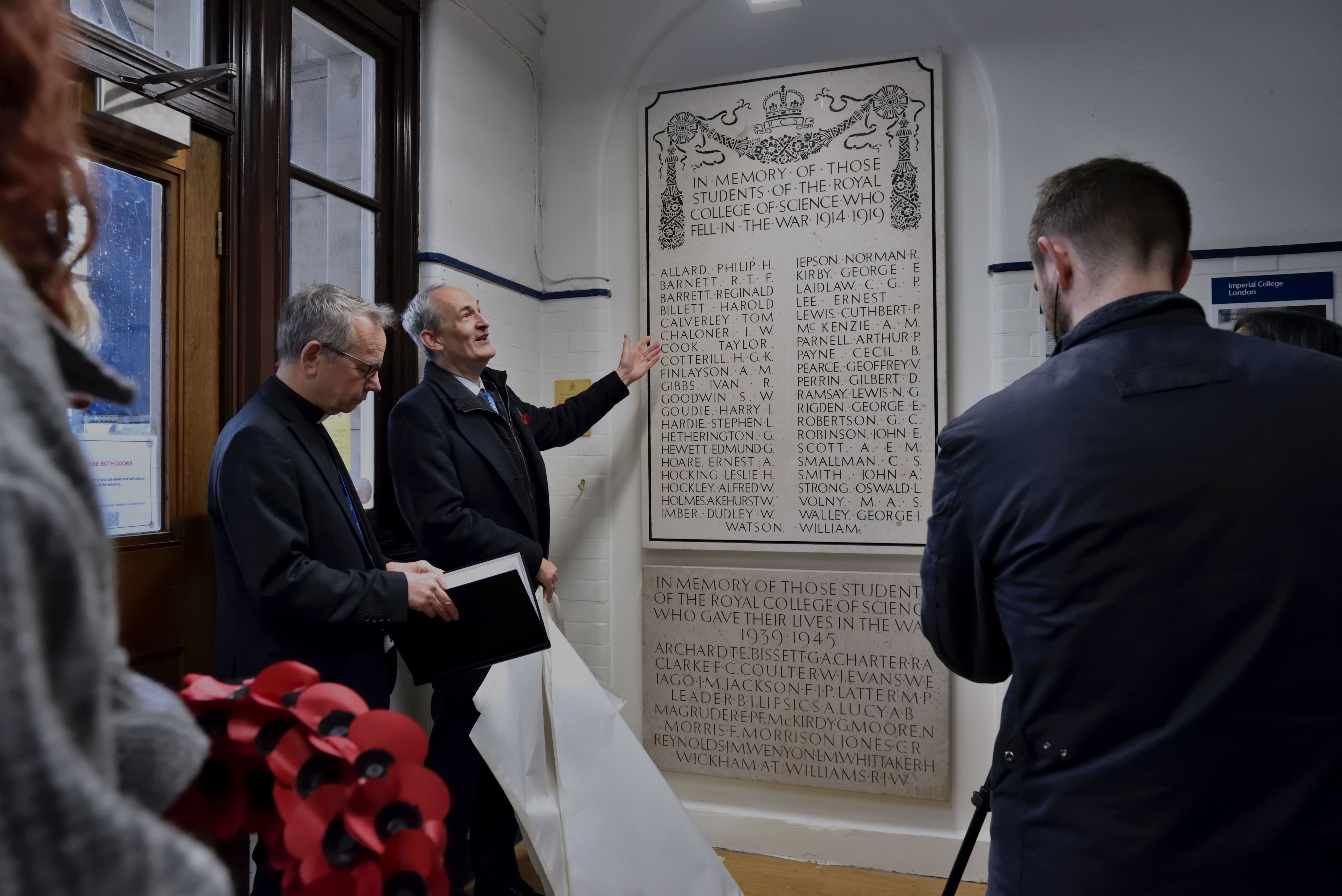 The college chaplain, standing next to the dean of the faculty of natural sciences (richard craster), unveiling the newly installed memorials on armistice day.