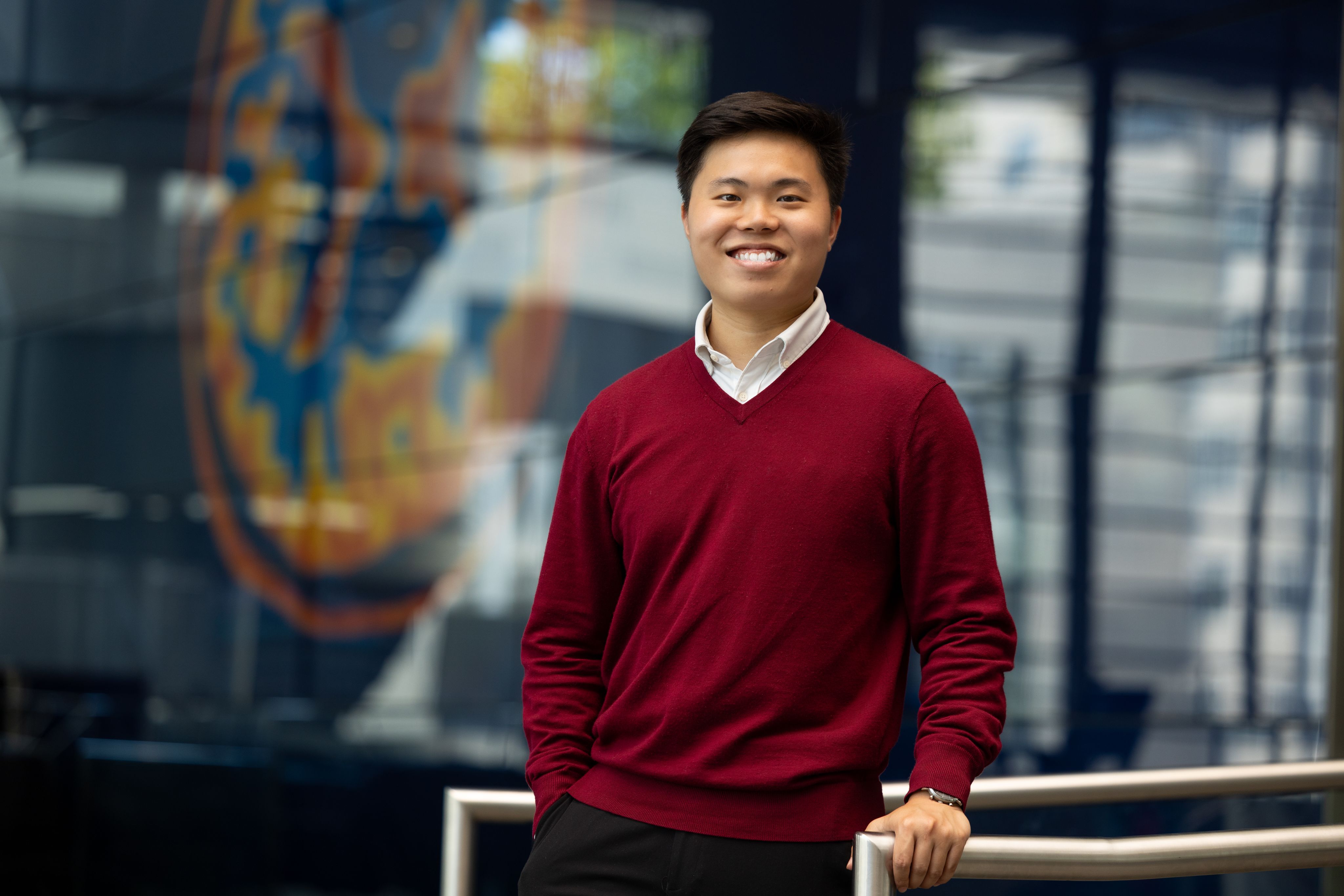 Han Ming standing in front of the MRI brain scan in South Kensington Campus' main entrance