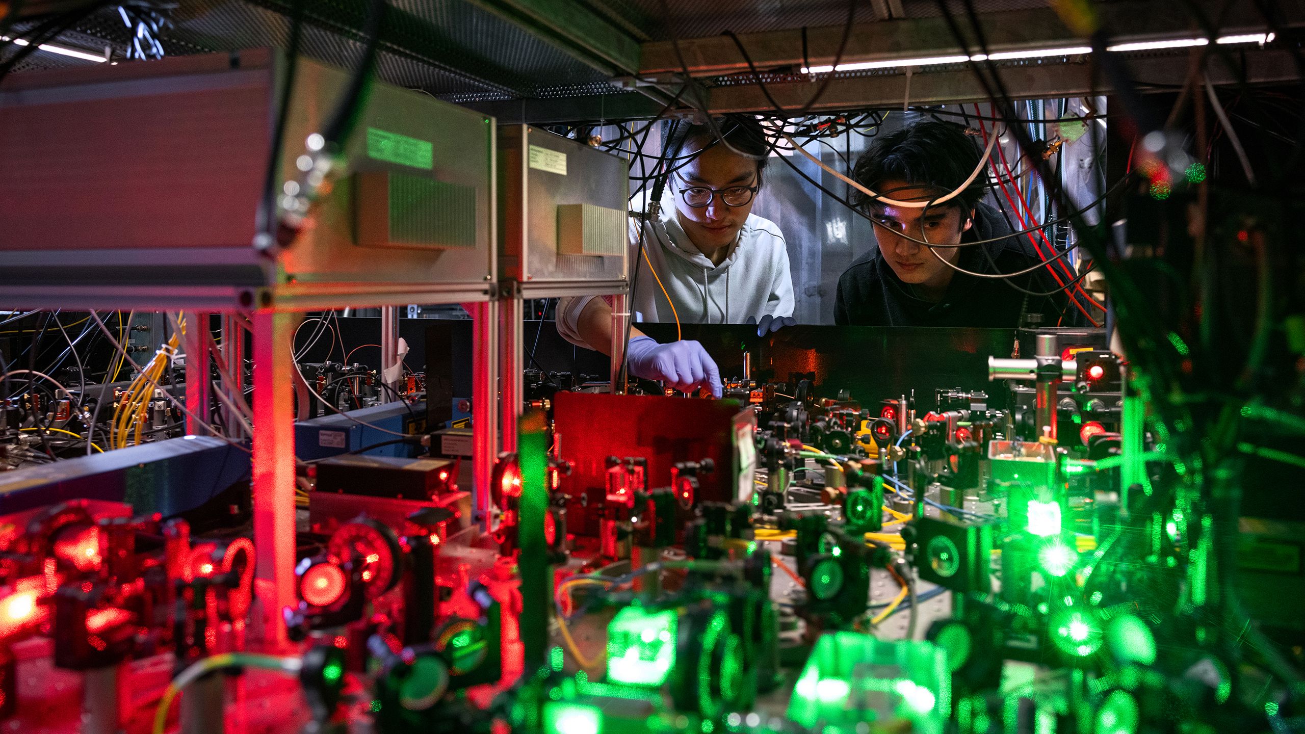Two Imperial scientists examine lasers on an optical table 