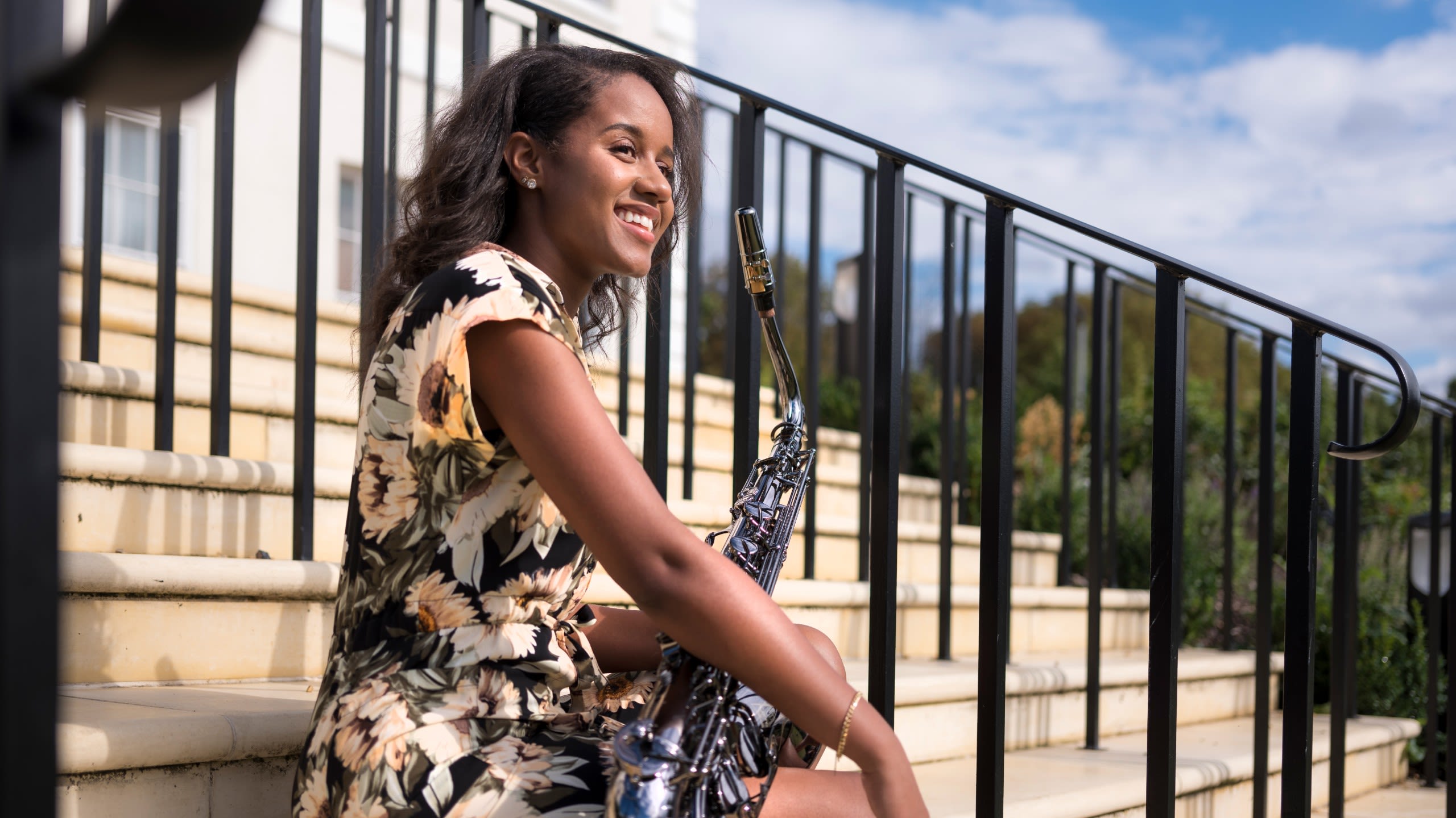 Gabrielle smiles and looks off in the distance holding a musical instrument.