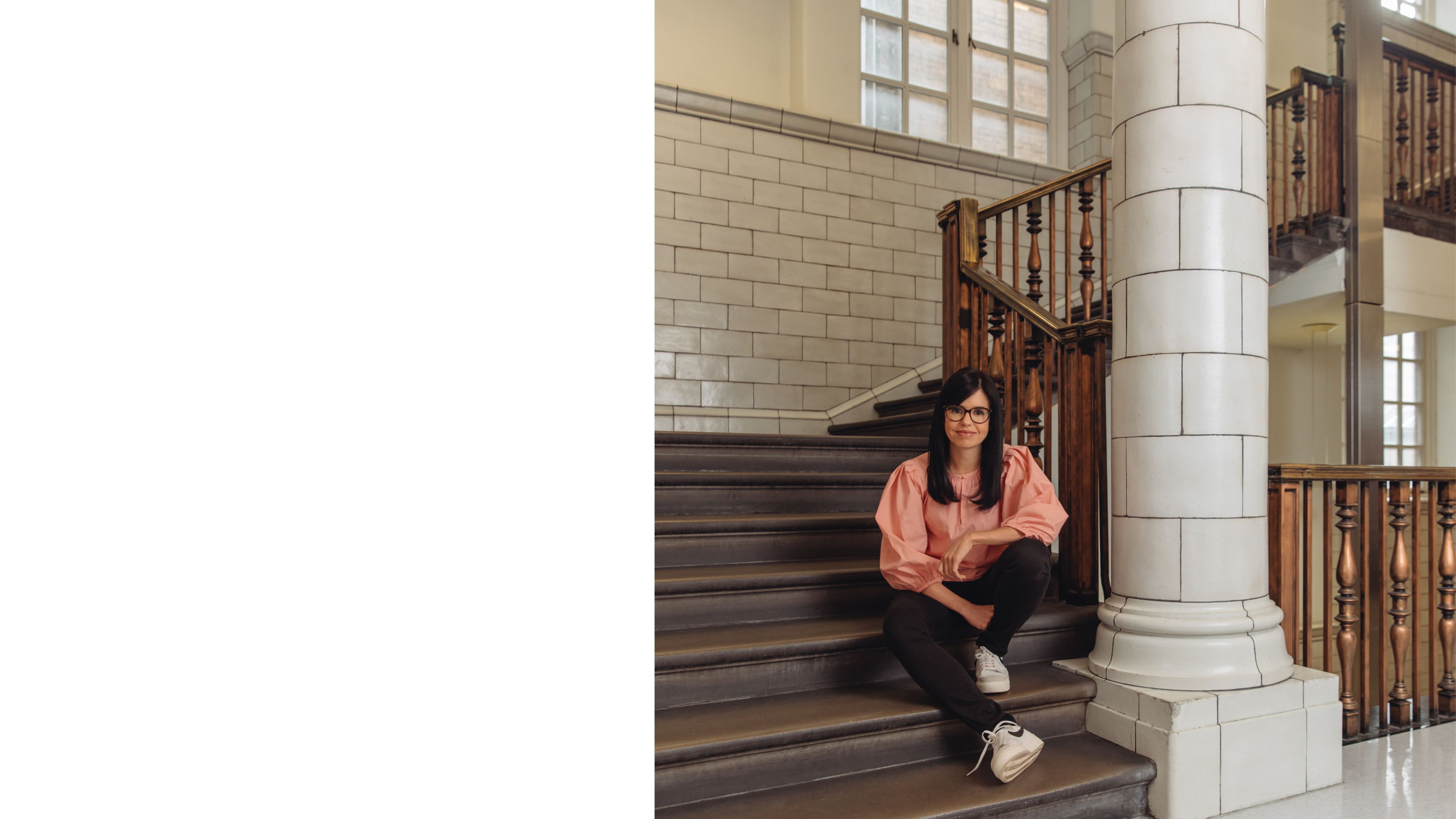 Jess, a woman with dark hair and glasses, sits on the steps inside the Royal School of Mines.