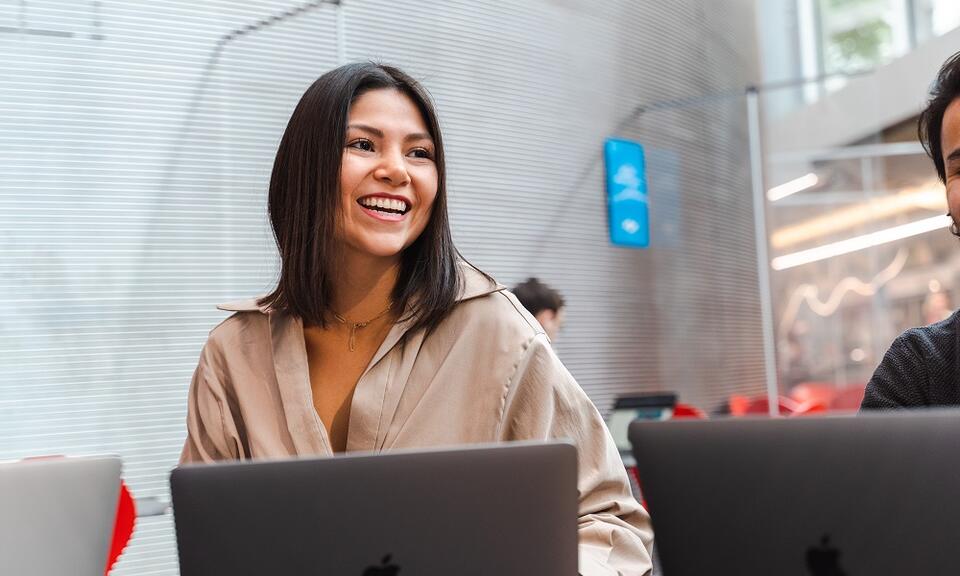 A young woman on a mac laptop smiling