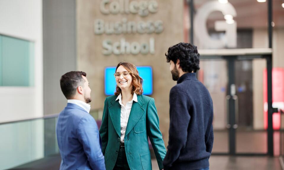 Students stand inside the main building of Imperial College Business School. 