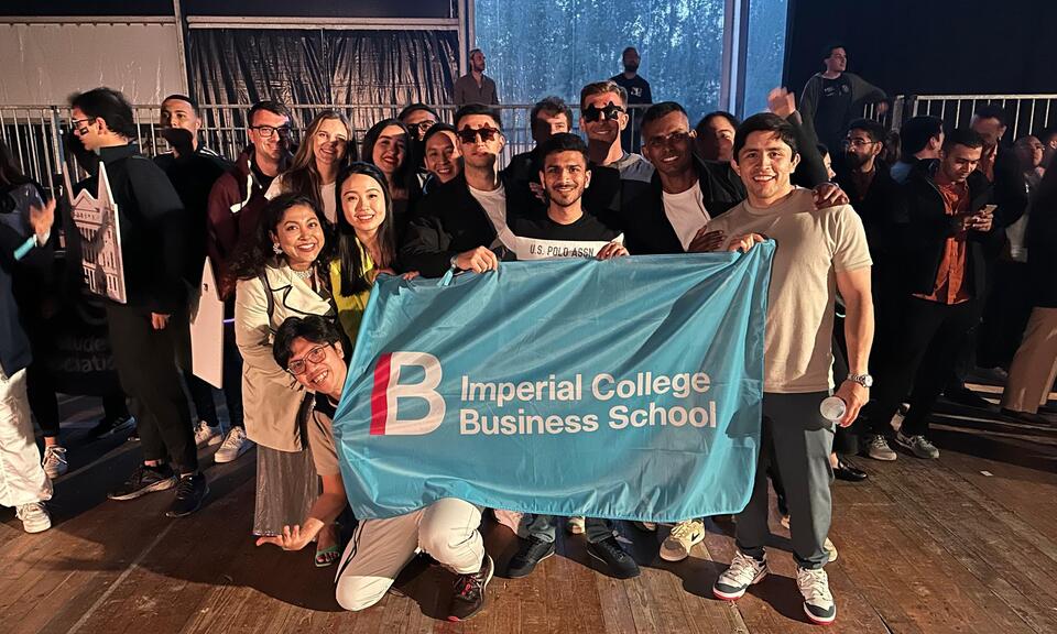Students pose with Imperial College Business School flag at MBAT