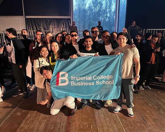 Students pose with Imperial College Business School flag at MBAT